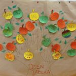 Fotografia przedstawia drzewo wykonane na arkuszu szarego papieru. Pień drzewa oraz konary narysowane zostały pisakiem. Na drzewie umieszczono jabłka w trzech kolorach- żółtym, czerwonym i zielonym. Każde jabłko zawiera wyraz określające ten owoc, który wcześniej posłużył uczniom klasy 1b do globalnego czytania.