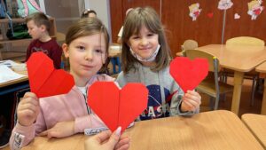  Na zdjęciu widzimy dwie dziewczynki trzymające w rękach serce wykonane metodą origami.