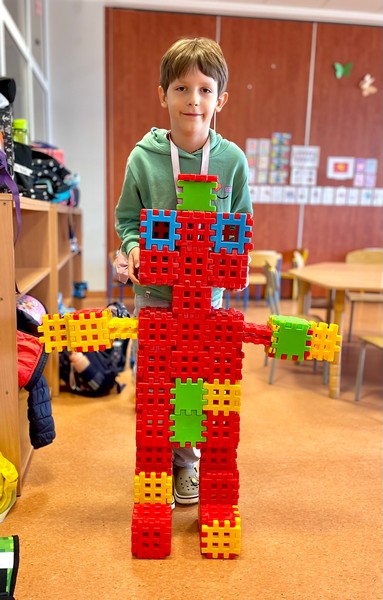 chłopiec prezentuje zbudowanego przez siebie robota z klocków.