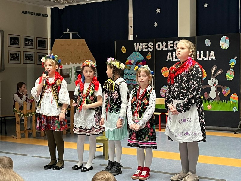 Pięć dziewczynek na scenie w ludowych strojach prezentuje wielkanocne wierszyki.