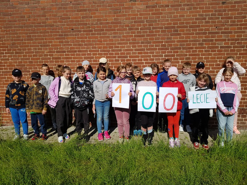 Uczniowie klasy IIIa na tle dawnego budynku szkoły prezentują napis 100 lecie.