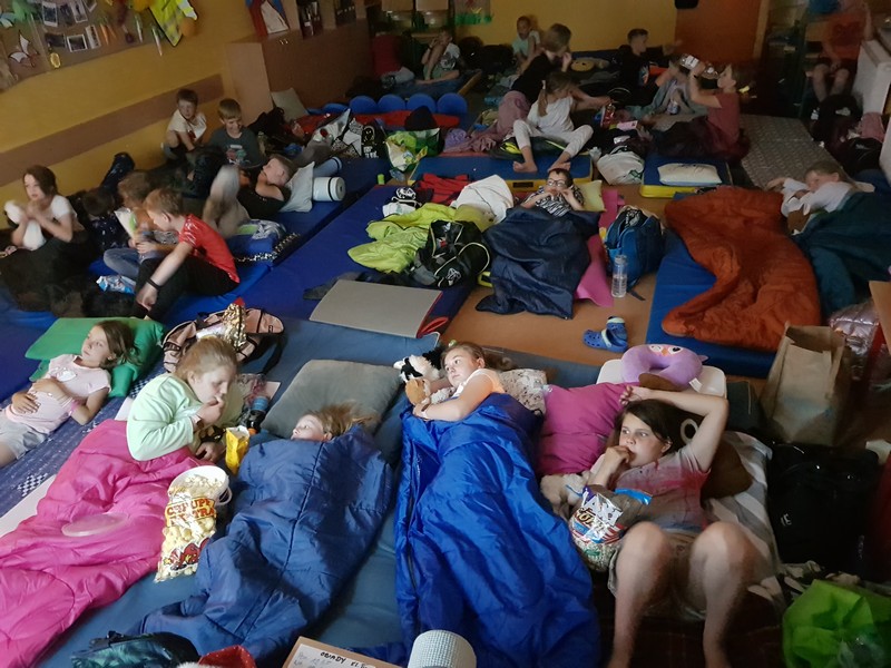 dzieci leżąc na posłaniach oglądają film